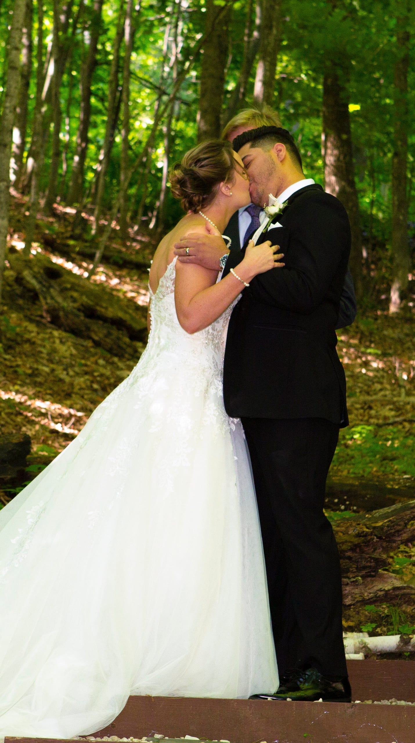 A bride and groom kiss in the woods
