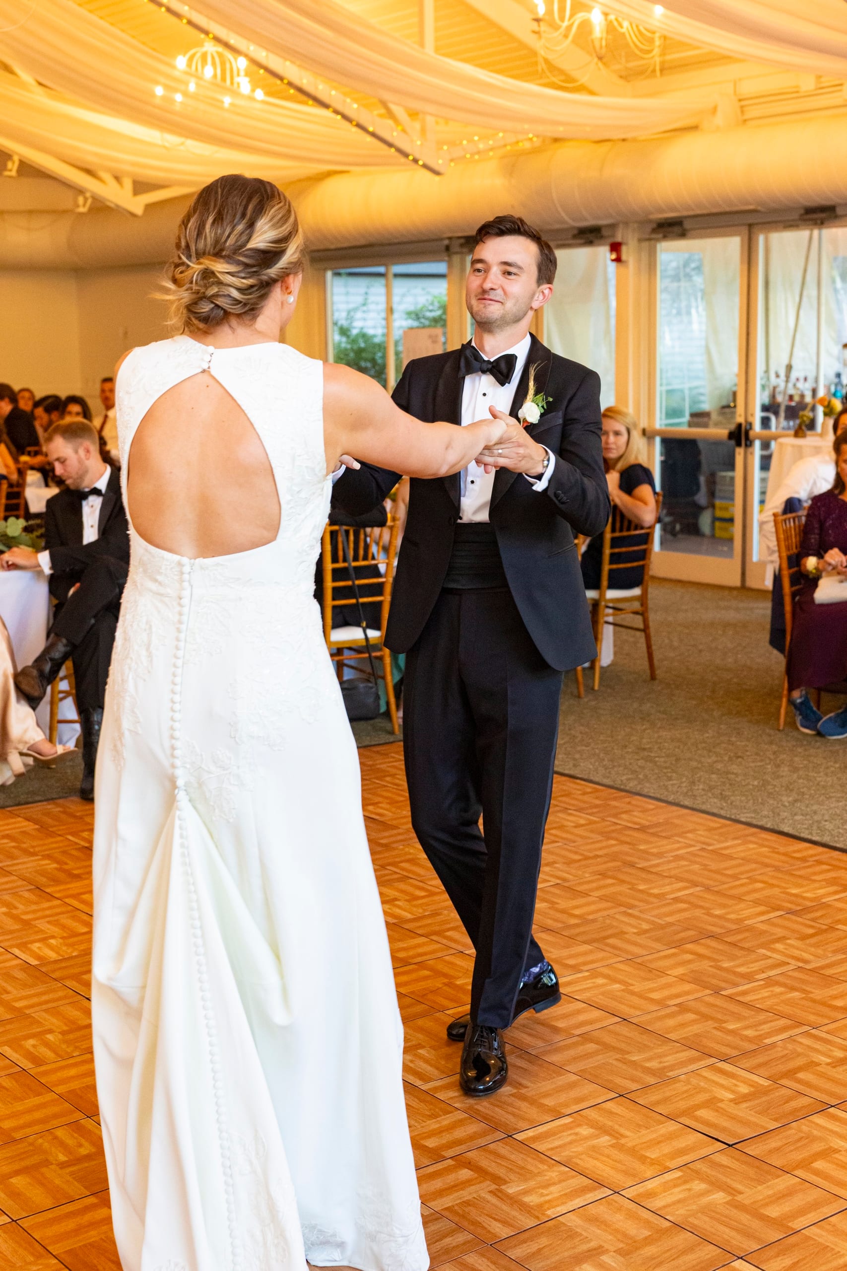 A bride and groom dance at their reception under a draped ceiling